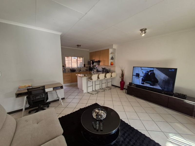 Open-plan living area featuring a kitchen with granite countertops, breakfast bar, and tiled flooring throughout, creating a functional and connected living space.