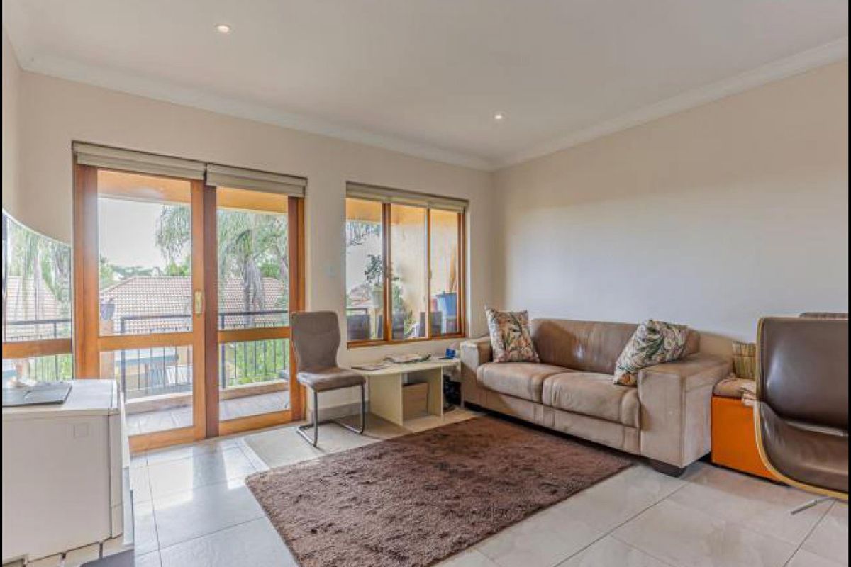 A bright living room featuring tiled flooring, recessed downlights, and sliding glass doors that provide direct access to an outdoor balcony area.