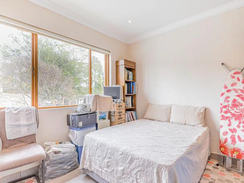 A bedroom featuring a large timber-framed window, recessed downlighting, and coved cornicing, offering a functional space with natural light.