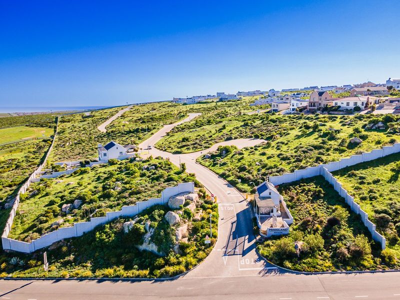Aerial view of the Hoogland Estate entrance, featuring a security gatehouse, perimeter walling, and paved access roads within a landscaped residential development.