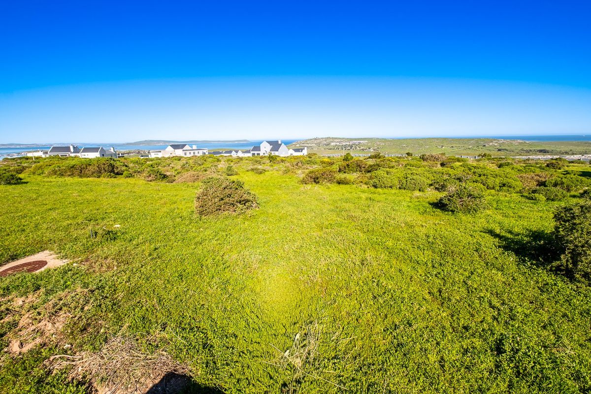 A wide-angle view of the vacant residential land featuring natural coastal vegetation and distant ocean views.