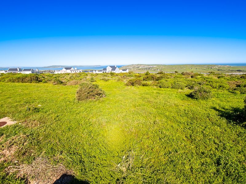 A wide-angle view of the vacant residential land featuring natural coastal vegetation and distant ocean views.