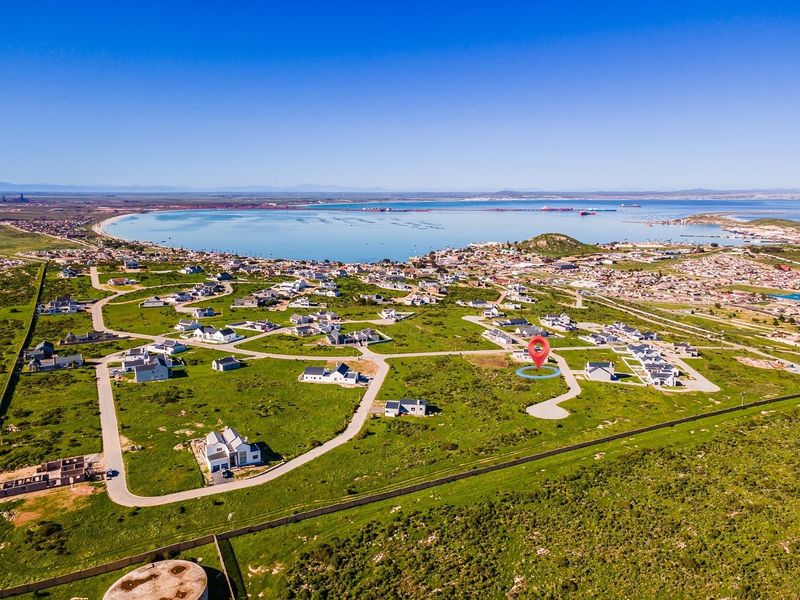 Aerial view of a residential development plot situated in a coastal estate with established road infrastructure and scenic bay views.