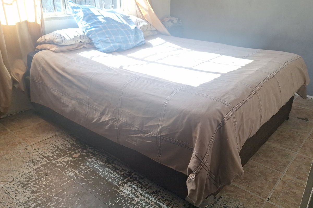 A bedroom featuring tiled flooring with visible wear and tear, providing a functional space that could benefit from cosmetic updates.