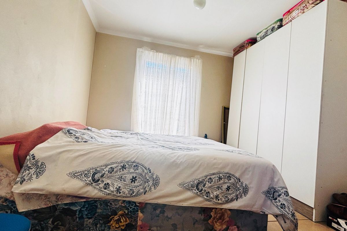 A bedroom featuring a large built-in wardrobe and neutral wall finishes, providing ample storage space.