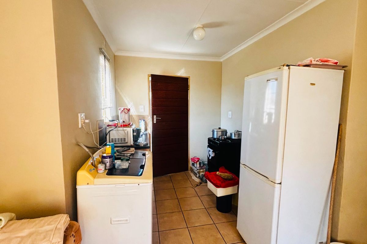 A functional kitchen area featuring tiled flooring, a single basin sink, and basic cabinetry, offering potential for modernization and layout optimization.