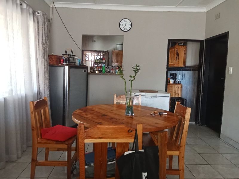 Open plan dining area featuring tiled flooring and a pass-through window connecting to the kitchen space.