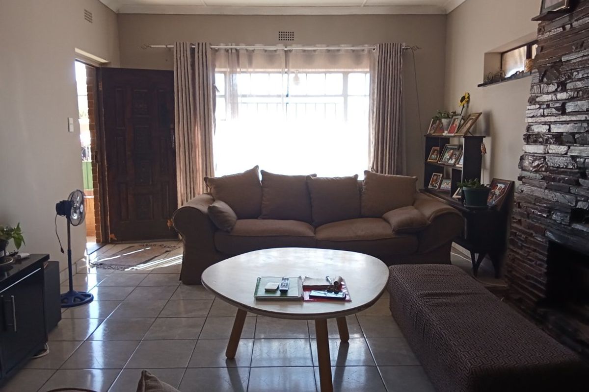 A living room featuring tiled flooring and a prominent stone fireplace, with direct access to the front entrance.