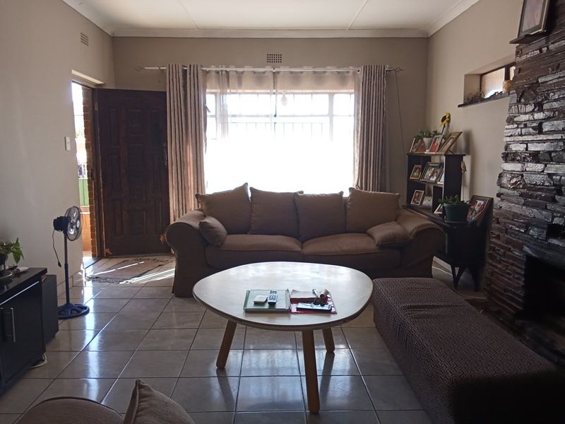 A living room featuring tiled flooring and a prominent stone fireplace, with direct access to the front entrance.
