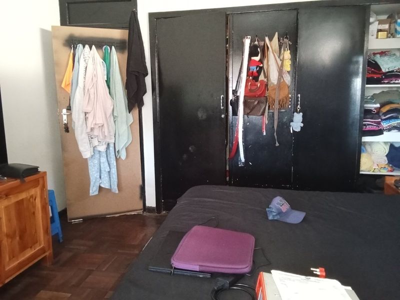 A bedroom featuring dark built-in cupboards and traditional parquet flooring, requiring cosmetic updates to improve the overall aesthetic and finish.