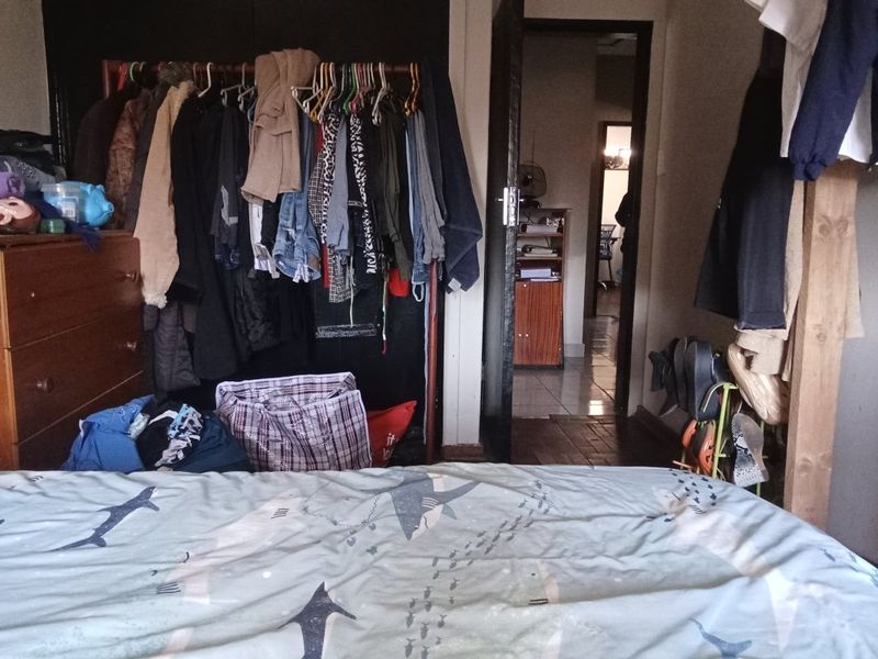 A bedroom featuring a built-in cupboard and a doorway leading to an adjacent room.