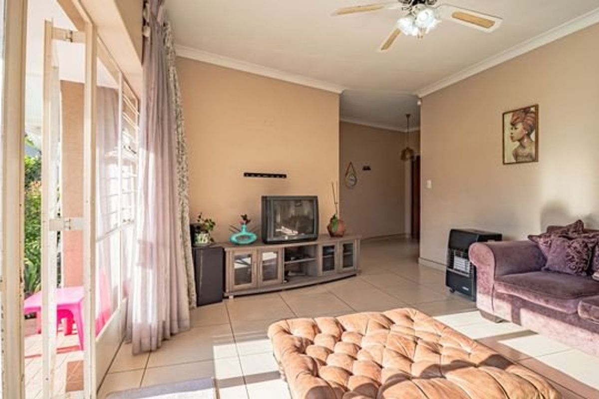 A bright living room featuring tiled flooring, a ceiling fan, and large sliding glass doors that provide direct access to the outdoor patio area.