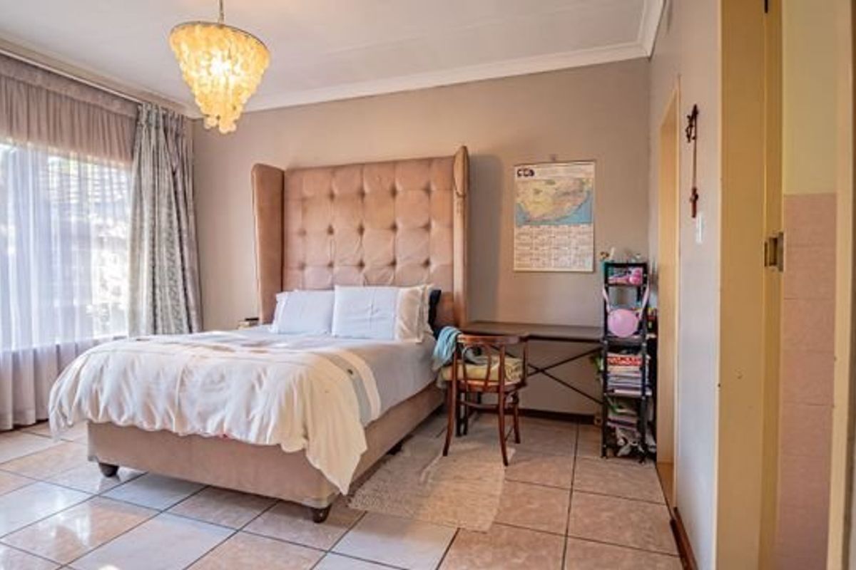 A spacious bedroom featuring tiled flooring, coved ceilings, and large windows with curtain tracks, offering a neutral base for personalization.