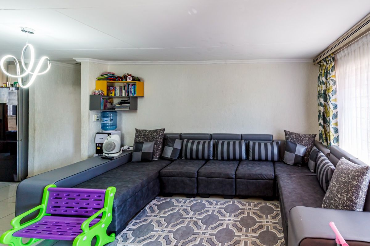 A living room area featuring tiled flooring and a modern light fixture, providing a functional space for relaxation.