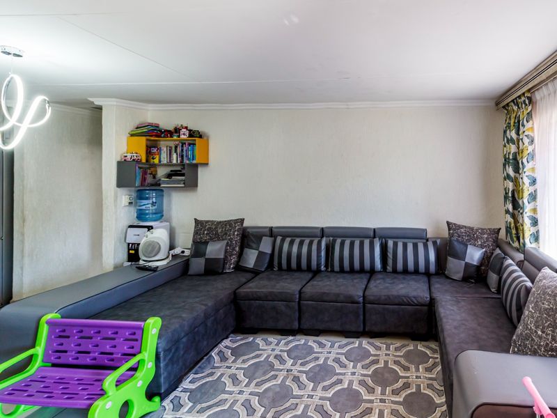 A living room area featuring tiled flooring and a modern light fixture, providing a functional space for relaxation.