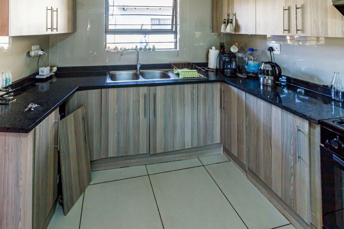 A functional kitchen featuring granite countertops, tiled backsplash, and wood-finish cabinetry, currently requiring minor repairs to a detached cabinet door.