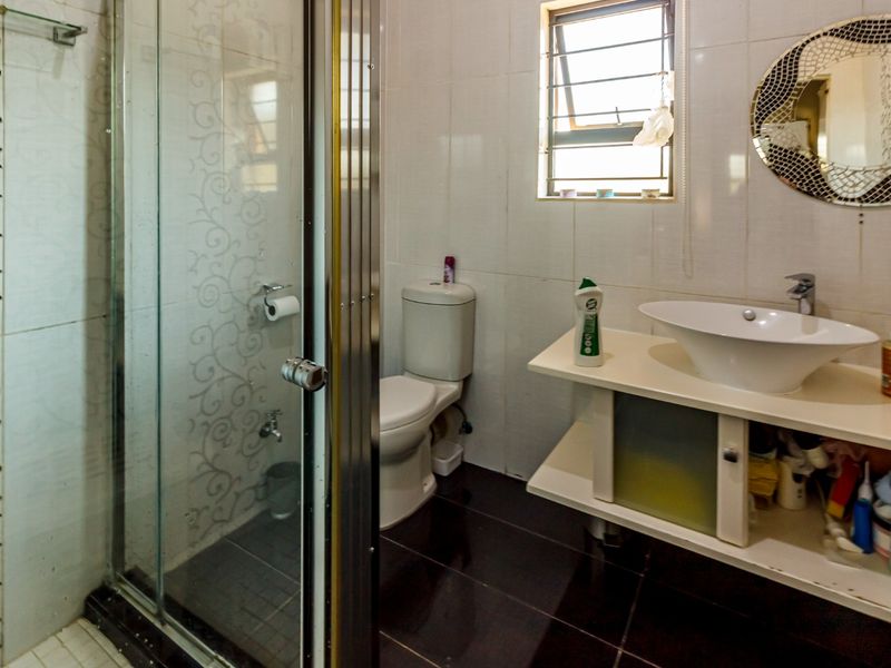 A functional bathroom featuring a glass-enclosed shower, a modern vessel sink on a vanity unit, and tiled finishes throughout.
