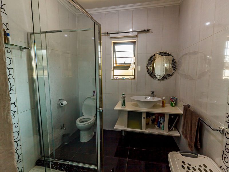 A functional bathroom featuring a glass shower enclosure, a modern vessel sink on a vanity unit, and tiled finishes throughout.