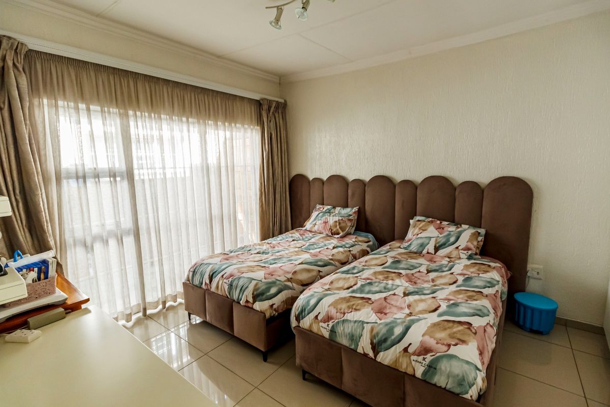 A bedroom featuring tiled flooring and large windows with curtain tracks, providing natural light and a functional layout.