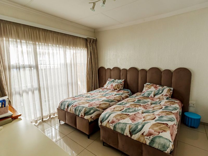 A bedroom featuring tiled flooring and large windows with curtain tracks, providing natural light and a functional layout.