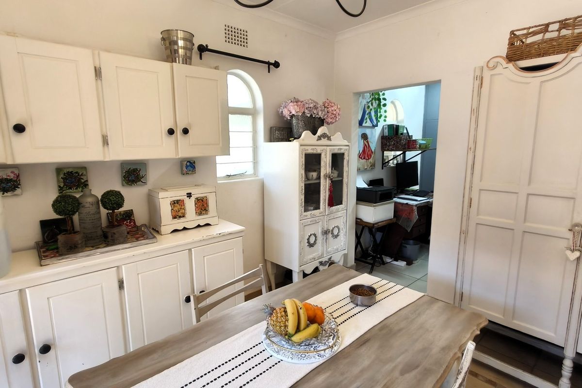 A functional kitchen area featuring white built-in cabinetry, an arched window, and a connected utility space, offering a bright and traditional aesthetic.