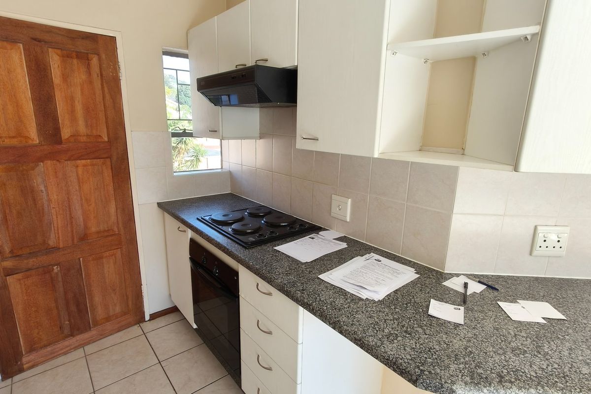 A functional kitchen featuring white cabinetry, granite-look laminate countertops, a built-in oven with hob, and tiled splashbacks.