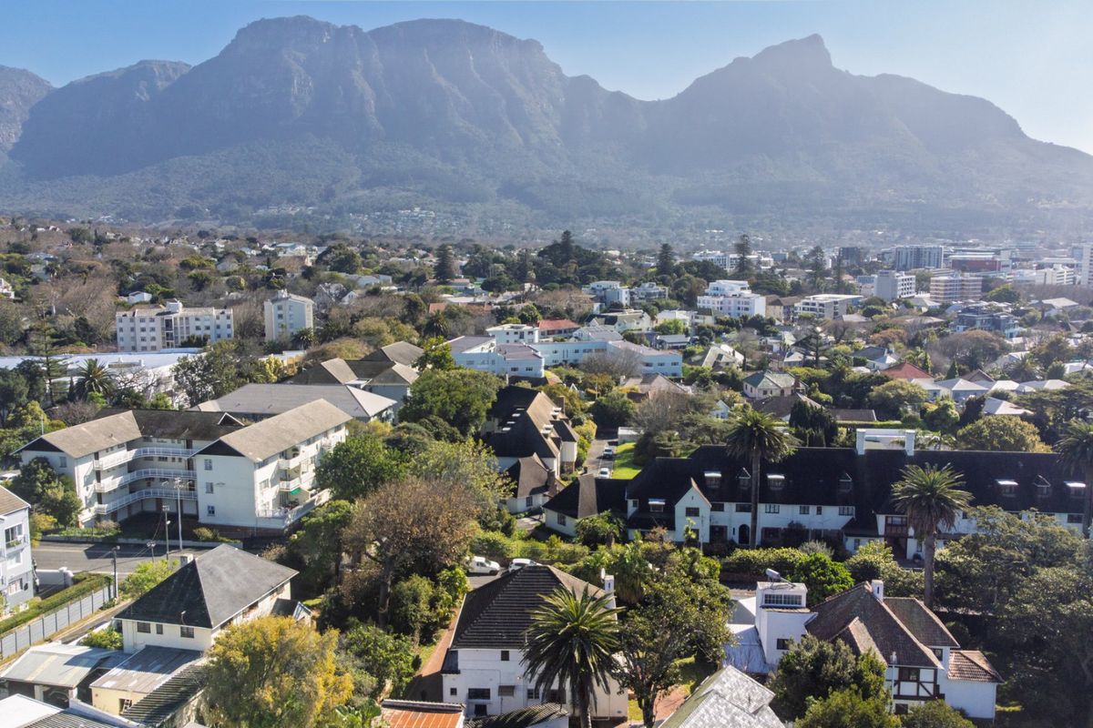 An elevated aerial view showcasing the surrounding neighbourhood and residential area with a prominent mountain backdrop.