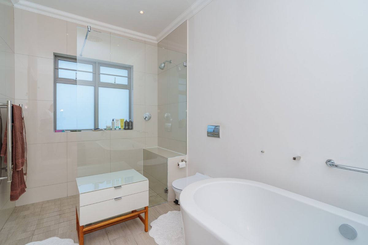 Modern bathroom featuring a sleek freestanding bathtub, a spacious walk-in shower with glass screen, wall-mounted toilet, and contemporary tiled finishes.