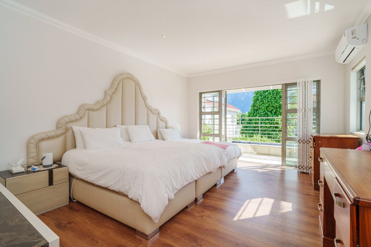 Spacious bedroom featuring laminate flooring, recessed lighting, a wall-mounted air conditioner, and sliding glass doors opening onto a private balcony.