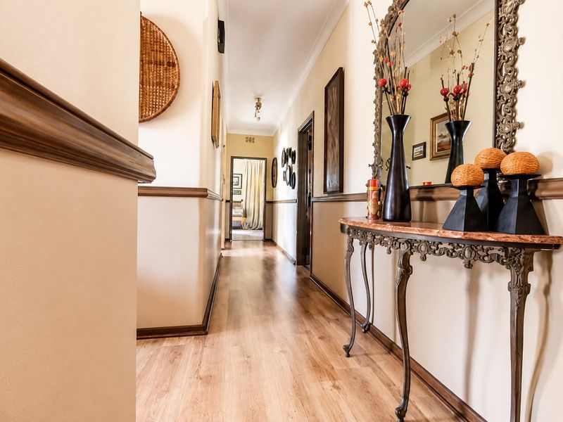 A well-maintained hallway featuring laminate flooring, decorative dado rails, and coving, providing a clean and welcoming transition between rooms.