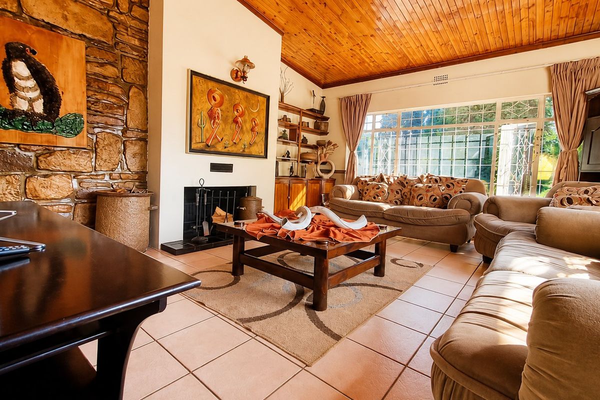 Spacious living room featuring a stone fireplace, warm timber ceiling, and large windows that provide ample natural light.