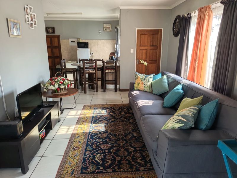 Open-plan living and kitchen area featuring tiled flooring, a breakfast bar, and direct access to adjacent rooms.