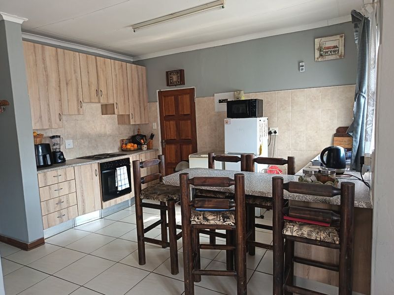 Functional kitchen featuring light wood-look cabinetry, tiled backsplash, built-in oven and hob, and tiled flooring with an integrated breakfast bar area.