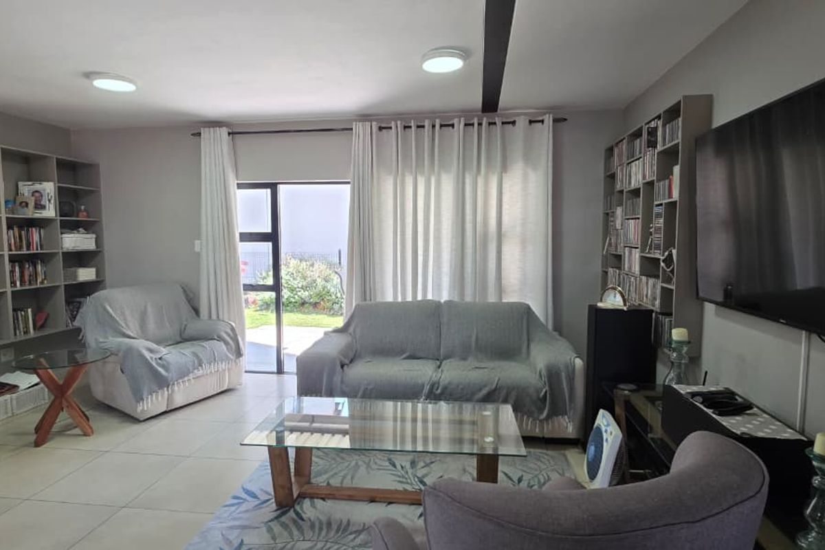 A comfortable living room featuring built-in shelving units, tiled flooring, and a sliding glass door providing access to the outdoor area.