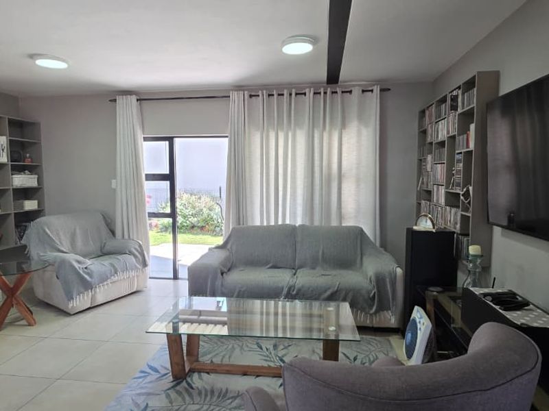 A comfortable living room featuring built-in shelving units, tiled flooring, and a sliding glass door providing access to the outdoor area.