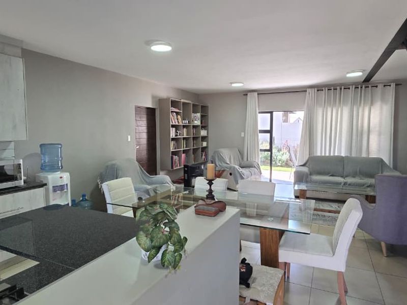 Open-plan living and kitchen area featuring tiled floors, granite countertops, built-in cabinetry, and a staircase, providing a functional and connected living space.
