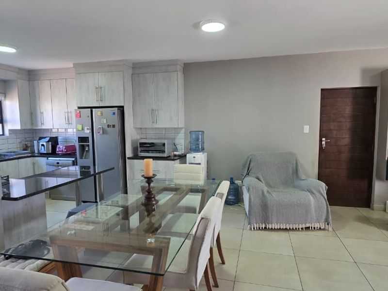 Spacious open-plan kitchen and dining area featuring modern cabinetry, granite countertops, and integrated shelving, providing a functional and well-lit living space.