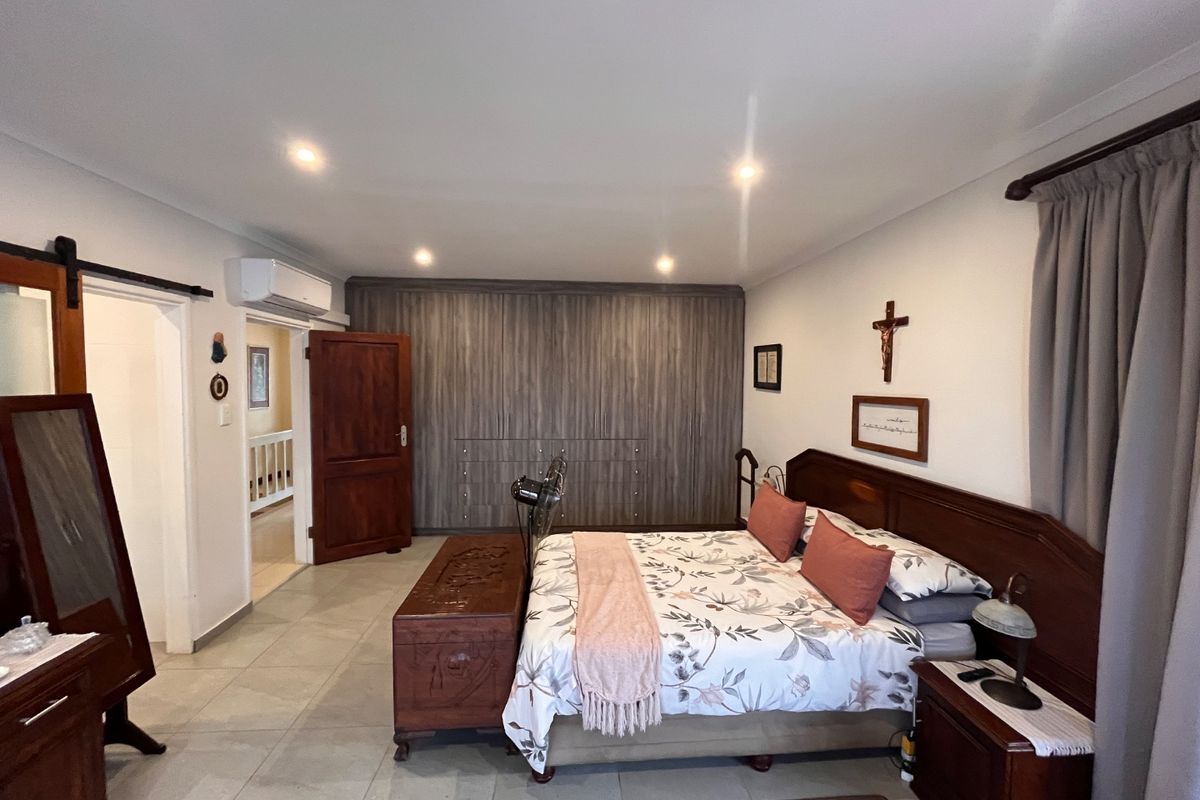 Spacious bedroom featuring tiled flooring, built-in cupboards, and a wall-mounted air conditioning unit.
