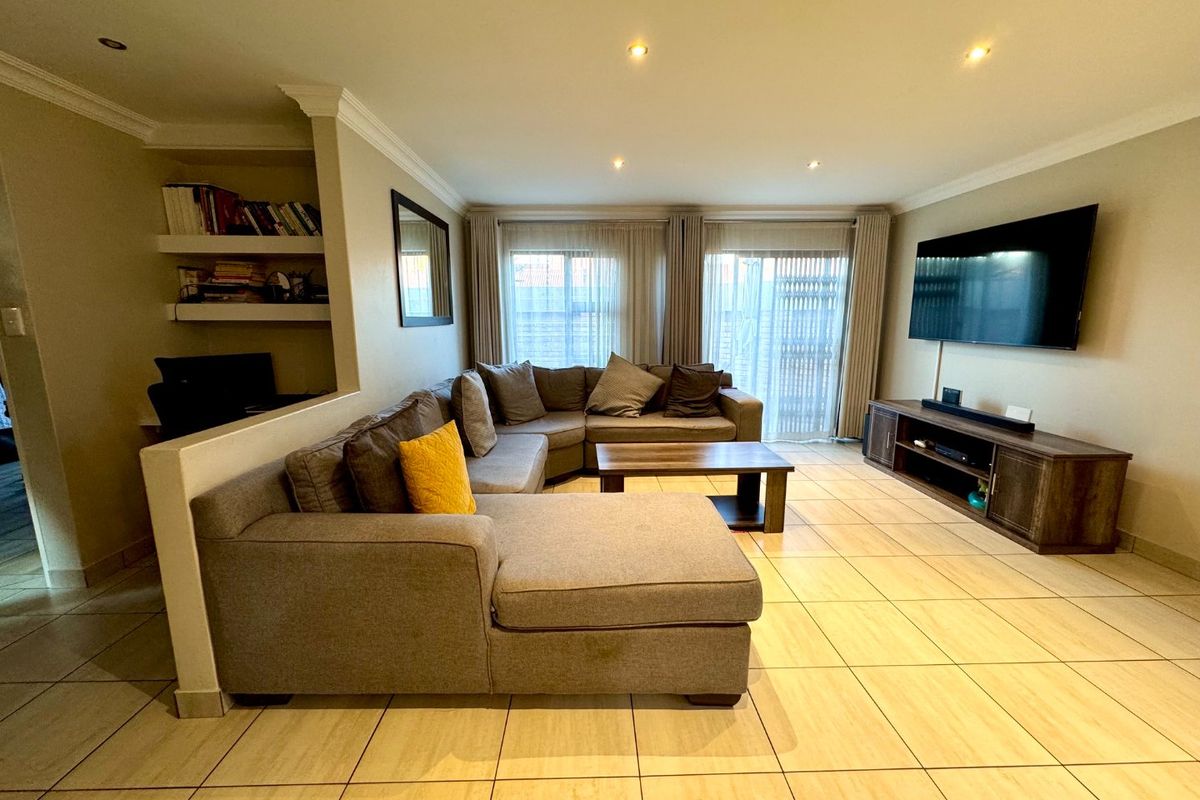 A well-maintained living room featuring tiled flooring, recessed downlighting, built-in shelving, and sliding glass doors providing access to the exterior.