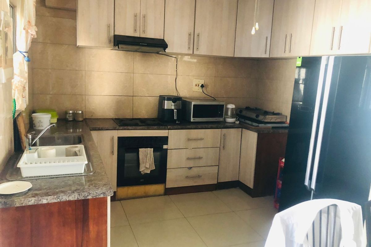 Functional kitchen featuring laminate cabinetry, granite countertops, built-in oven, extractor fan, and tiled backsplash with neutral floor tiling.