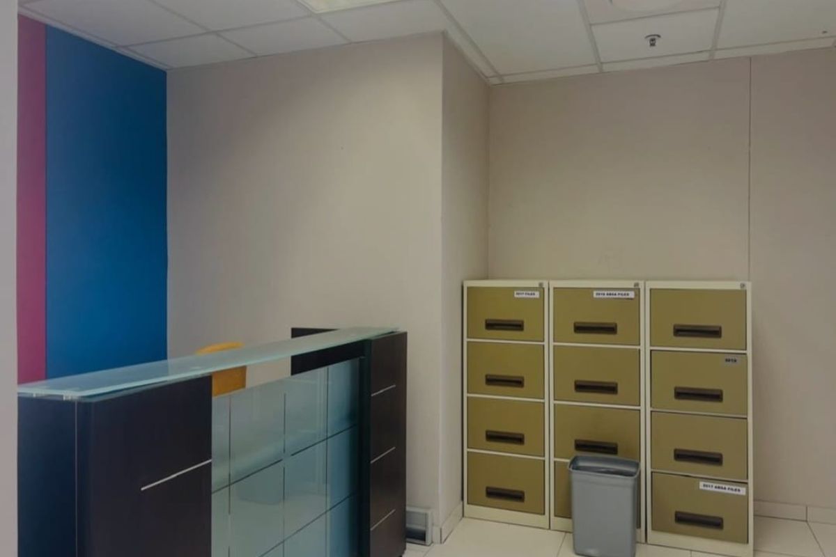 A commercial office space featuring a reception desk, tiled flooring, and a suspended ceiling, suitable for administrative or client-facing operations.