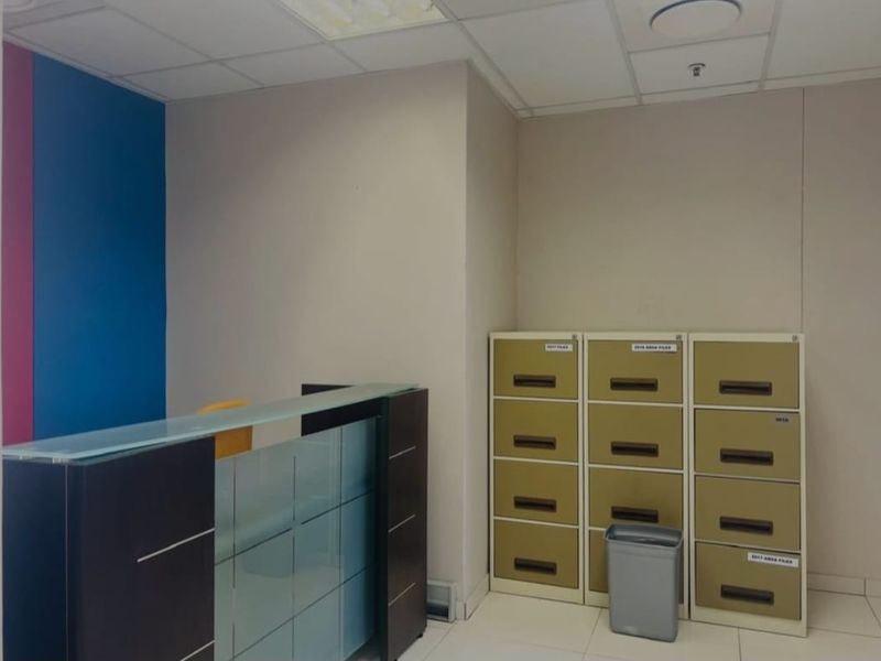 A commercial office space featuring a reception desk, tiled flooring, and a suspended ceiling, suitable for administrative or client-facing operations.
