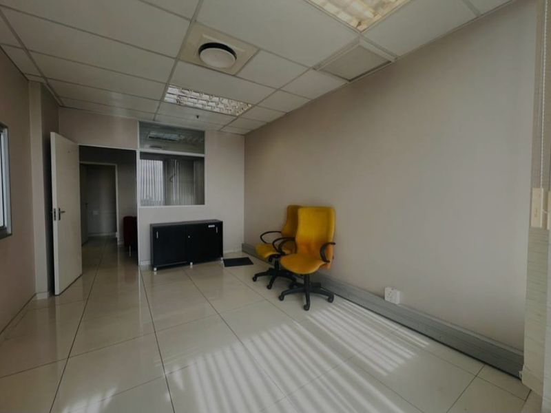 A commercial office space featuring tiled flooring, a suspended ceiling with recessed lighting, and an internal glass partition wall.