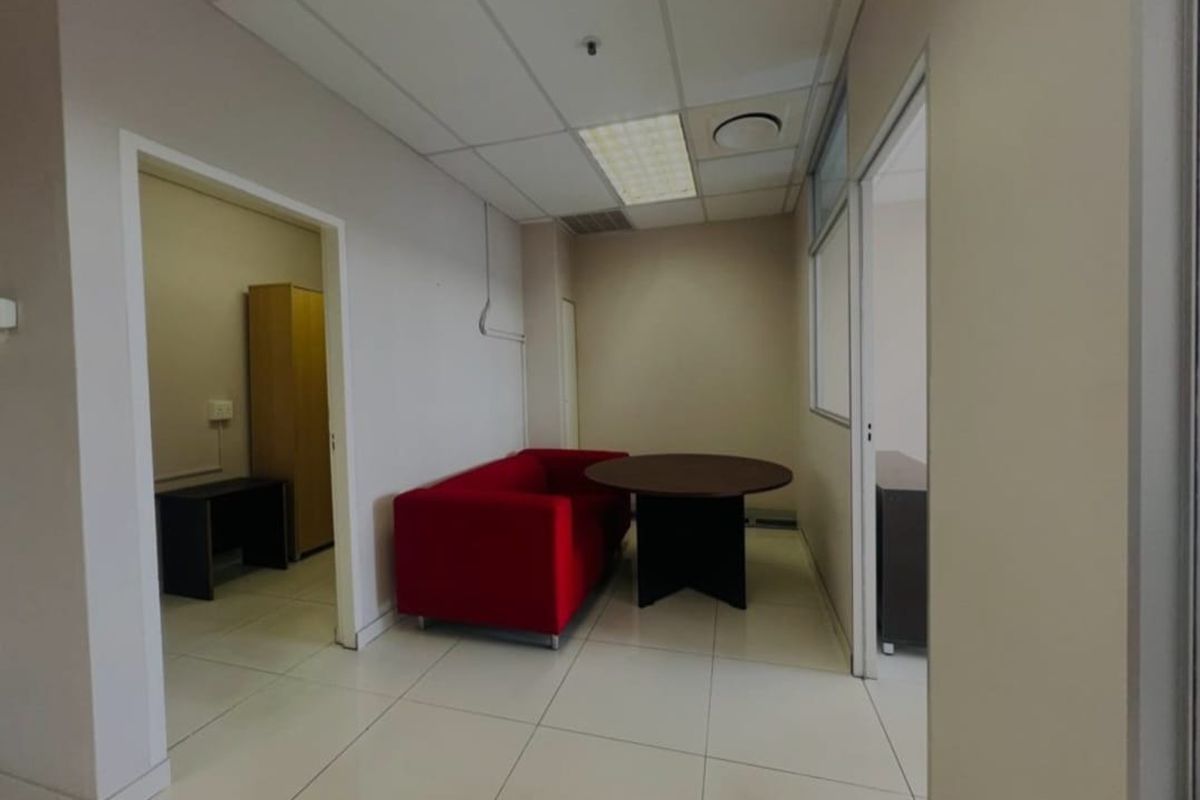 A functional commercial office space featuring neutral wall finishes, tiled flooring, and a suspended ceiling with integrated lighting.