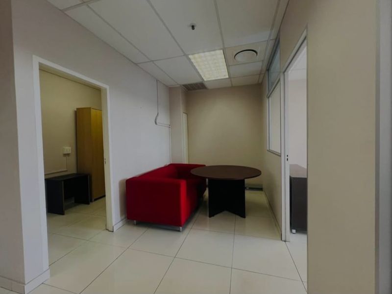 A functional commercial office space featuring neutral wall finishes, tiled flooring, and a suspended ceiling with integrated lighting.