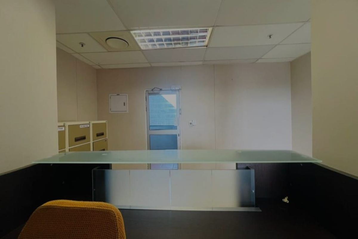 A functional commercial office space featuring a suspended ceiling, recessed lighting, and a glass door providing access to the exterior.
