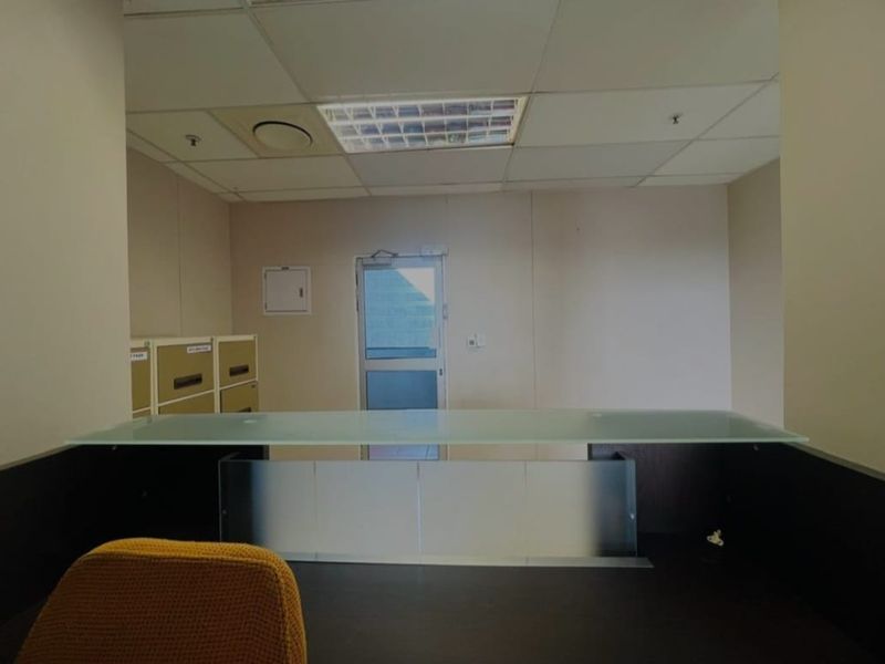 A functional commercial office space featuring a suspended ceiling, recessed lighting, and a glass door providing access to the exterior.