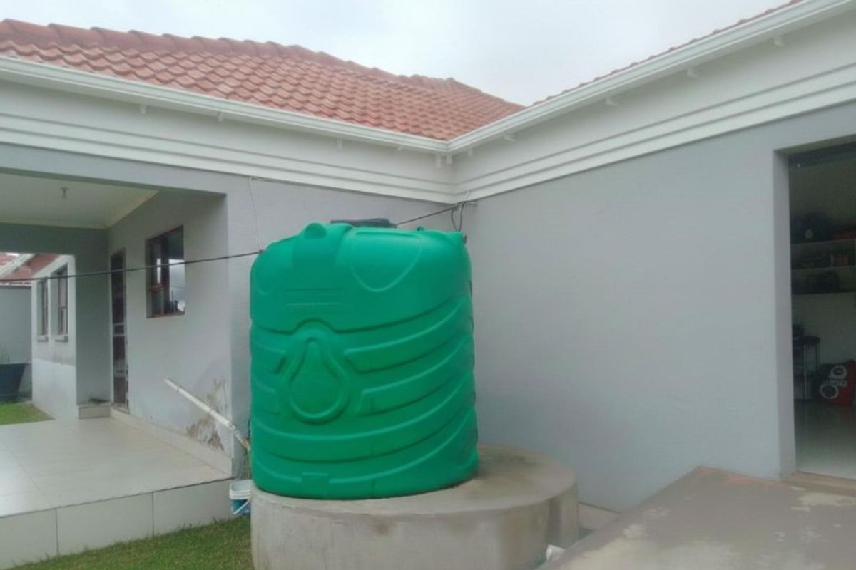 Rear exterior view of the property featuring a water storage tank on a concrete plinth and tiled roof structure.