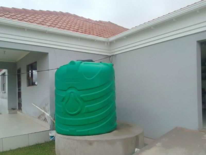 Rear exterior view of the property featuring a water storage tank on a concrete plinth and tiled roof structure.