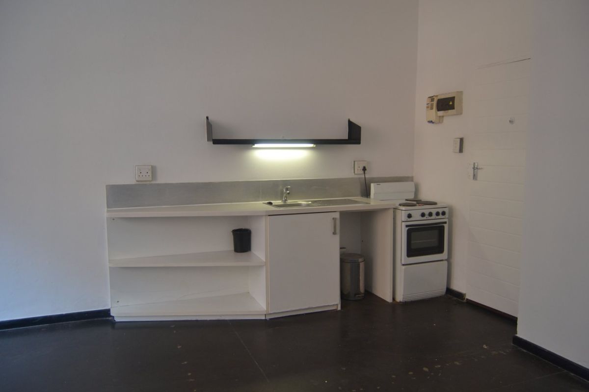 A compact, functional kitchen area featuring basic cabinetry, a stainless steel sink, and a freestanding stove, suitable for a studio or small apartment.